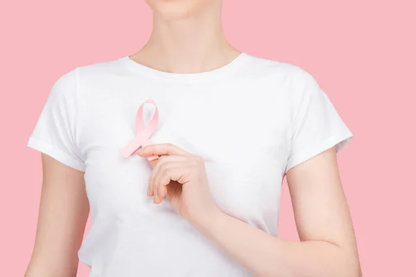 Visión parcial de la mujer en camiseta blanca sosteniendo signo de cáncer de mama rosa aislado en rosa - foto de stock