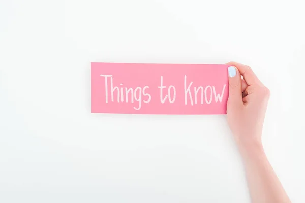 Vista parcial de la mujer sosteniendo tarjeta rosa con cosas para saber letras sobre fondo blanco - foto de stock