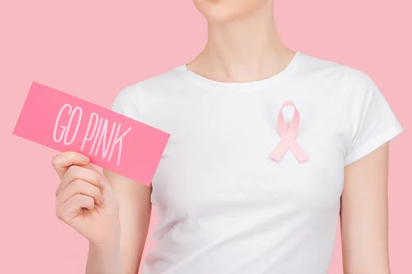 Cropped view of woman with pink breast cancer sign holding pink card with go pink lettering isolated on pink — Stock Photo