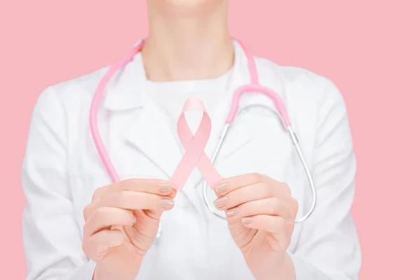 Selective focus of doctor in white coat holding pink breast cancer sign isolated on pink — Stock Photo