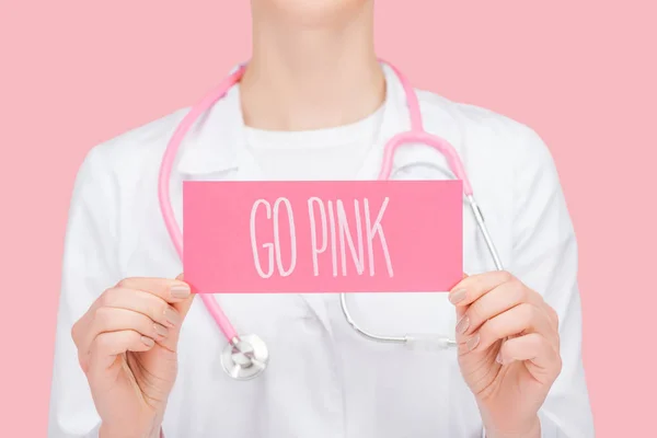 Teilansicht des Arztes in weißem Mantel und Stethoskop-Visitenkarte mit rosa Schriftzug isoliert auf rosa — Stockfoto