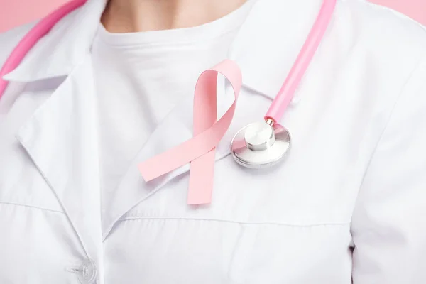 Vista de cerca del médico de bata blanca con signo de cáncer de mama rosa - foto de stock