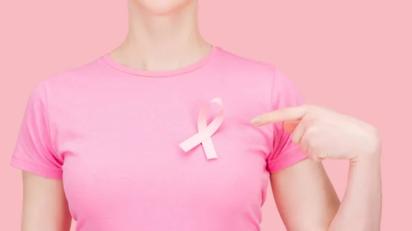 Cropped view of woman in pink t-shirt pointing with finger at silk breast cancer sing isolated on pink — Stock Photo