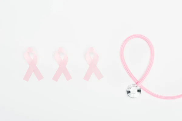 Flat lay with stethoscope and pink breast cancer signs on white background — Stock Photo