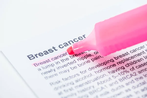 Vista de perto do jornal impresso com câncer de mama artigo e marcador rosa no fundo branco — Fotografia de Stock