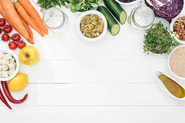 Vista superior de frutas y verduras cerca de frascos de vidrio en mesa blanca de madera con espacio para copiar — Stock Photo