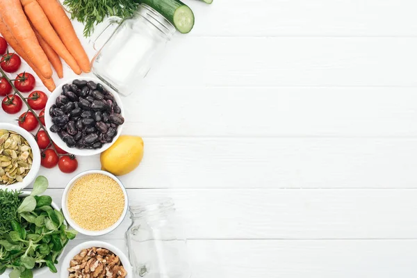 Top view of tasty fruits and vegetables near glass jars on wooden white table with copy space — Stock Photo