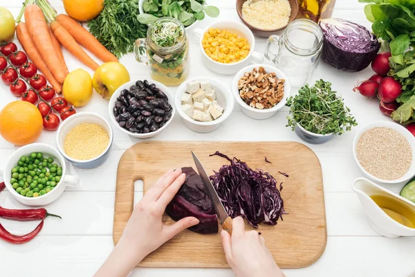 Vista recortada de la mujer cortando col roja en tabla de cortar de madera — Stock Photo