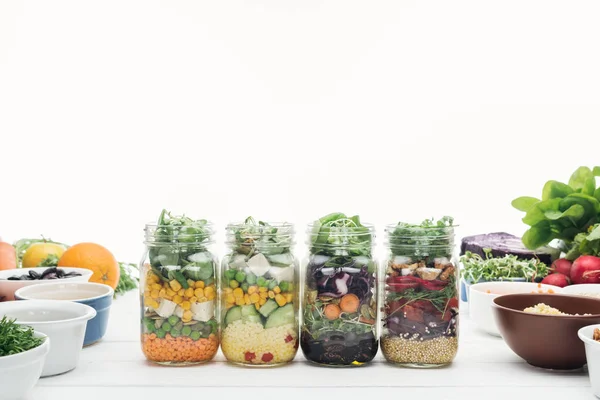 Salade de légumes frais dans des bocaux en verre sur table blanche en bois isolé sur blanc — Photo de stock