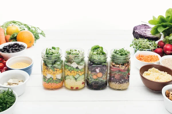 Salade de légumes dans des bocaux en verre sur table blanche en bois isolé sur blanc — Photo de stock