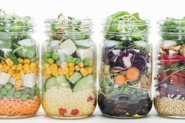 Salade de légumes frais dans des bocaux en verre isolés sur blanc — Photo de stock