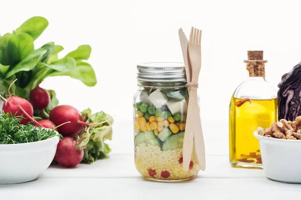 Frischer Gemüsesalat im Glas in der Nähe von Öl und Rettich isoliert auf weiß — Stockfoto