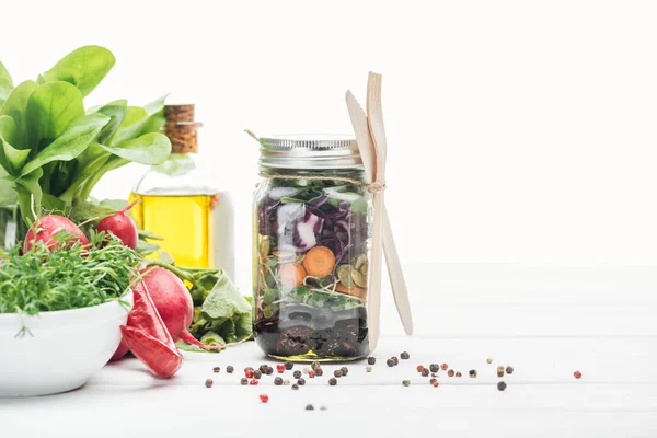 Salade de légumes frais dans un bocal en verre près des épices et radis isolé sur blanc — Photo de stock