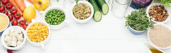 Tasty fruits and vegetables near glass jars on wooden white table with copy space, panoramic shot — Stock Photo