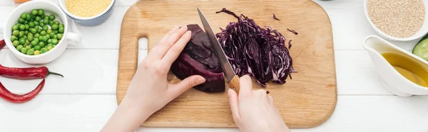 Cropped view of woman cutting red cabbage on wooden chopping board, panoramic shot — Stock Photo