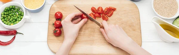 Visão parcial da mulher cortando tomates cereja em tábua de corte de madeira, tiro panorâmico — Fotografia de Stock