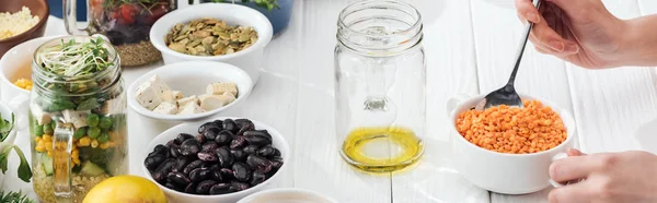 Vista recortada de la mujer añadiendo cuscús en frasco con aceite, tiro panorámico - foto de stock