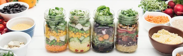 Délicieuse salade de légumes dans des bocaux en verre sur table blanche en bois isolé sur blanc, vue panoramique — Photo de stock