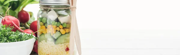 Plano panorámico de ensalada de verduras frescas en frasco de vidrio cerca de rábano aislado en blanco - foto de stock
