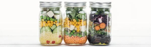 Köstlicher Gemüsesalat in Gläsern auf weißem Holztisch isoliert auf weißem, panoramischem Foto — Stockfoto