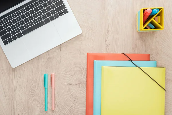 Vue de dessus de l'ordinateur portable, stylos et dossiers sur la table en bois — Photo de stock