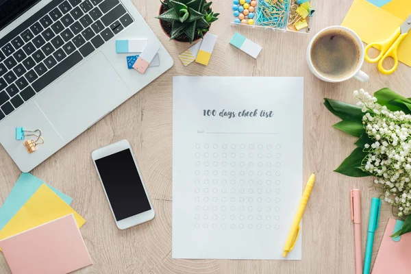 Top view of 100 days check list with smartphone, laptop and stationery on wooden table — Stock Photo