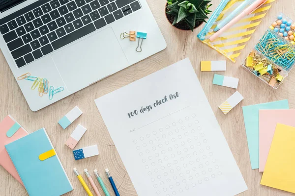 Vista superior da lista de verificação de 100 dias, artigos de papelaria e laptop na mesa de madeira — Fotografia de Stock