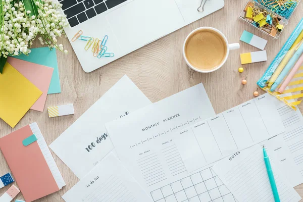 Top view of planners, stationery, cup of coffee and laptop on wooden table — Stock Photo