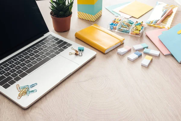 Bloco de notas, flor, artigos de papelaria e laptop em mesa de madeira — Fotografia de Stock