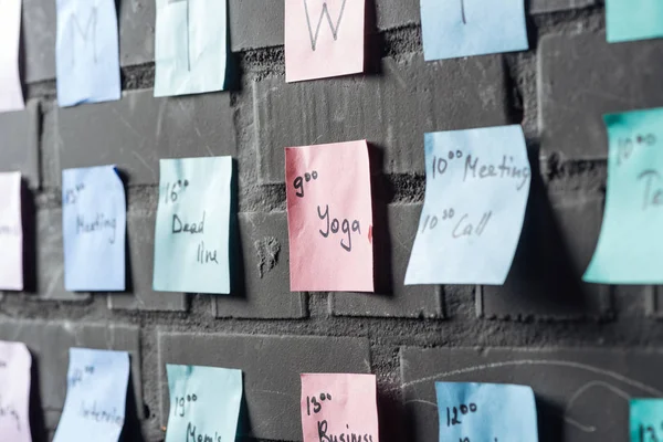 Mise au point sélective de notes autocollantes colorées sur un mur de briques noires — Photo de stock