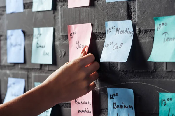 Cropped view of woman attach pink colorful sticker note on black brick wall — Stock Photo