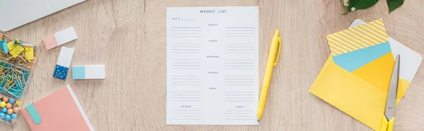 Panoramic view of weekly list and stationery on wooden table — Stock Photo
