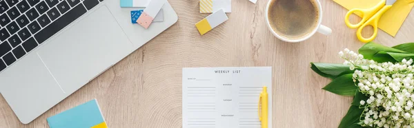 Vue panoramique du planificateur mensuel, fleurs, ordinateur portable et tasse à café sur table en bois — Photo de stock