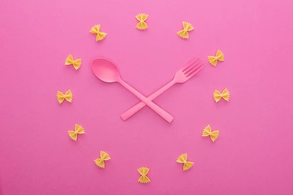 Concetto di orologio con forchetta incrociata in plastica rosa e cucchiaio isolato su rosa — Foto stock