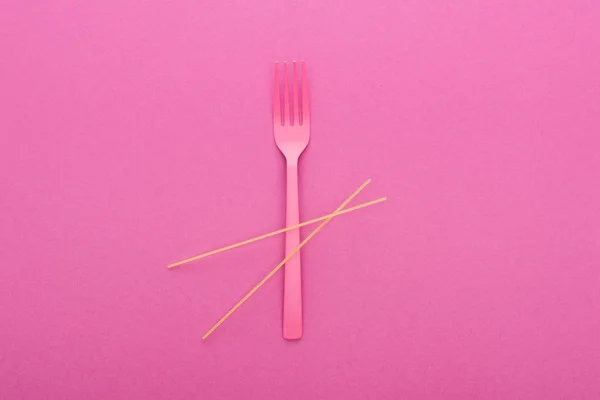 Vista superior de tenedor de plástico rosa y espaguetis aislados en rosa - foto de stock