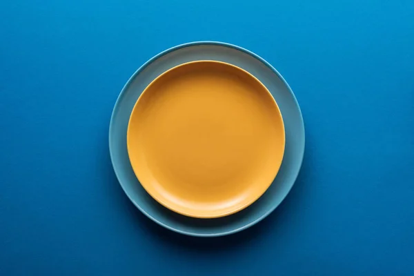 Вид сверху на голубую пластину под желтым на голубом фоне — стоковое фото