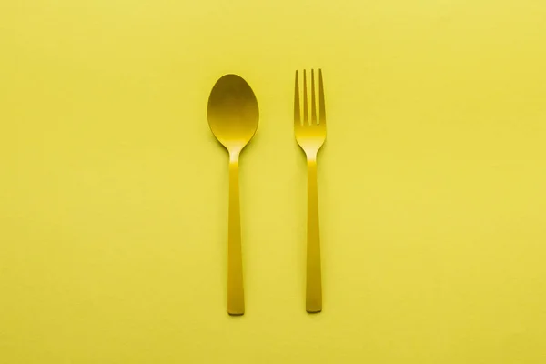 Top view of yellow spoon and fork isolated on yellow — Stock Photo