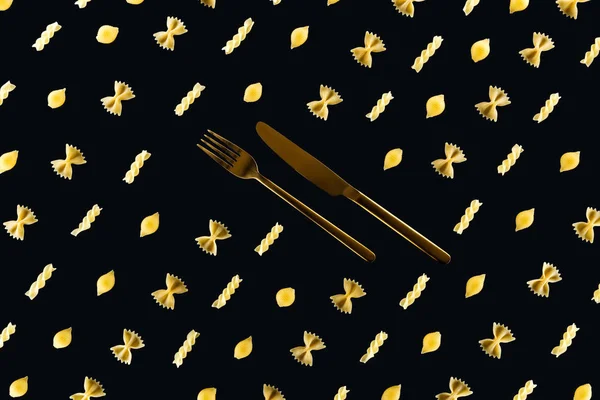 Flat lay of different kinds of pasta with metal cutlery in middle isolated on black — Stock Photo