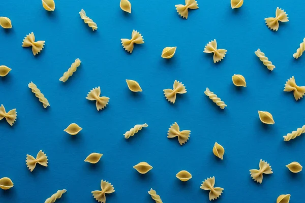 Draufsicht auf verschiedene ungekochte Pasta auf blauem Hintergrund — Stockfoto