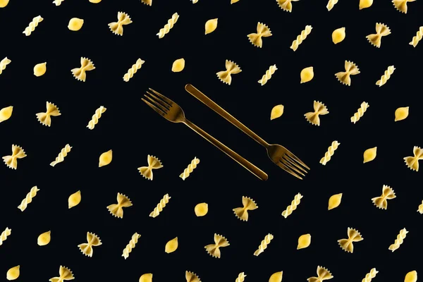Flat lay of different kinds of pasta with two metal forks in middle isolated on black — Stock Photo