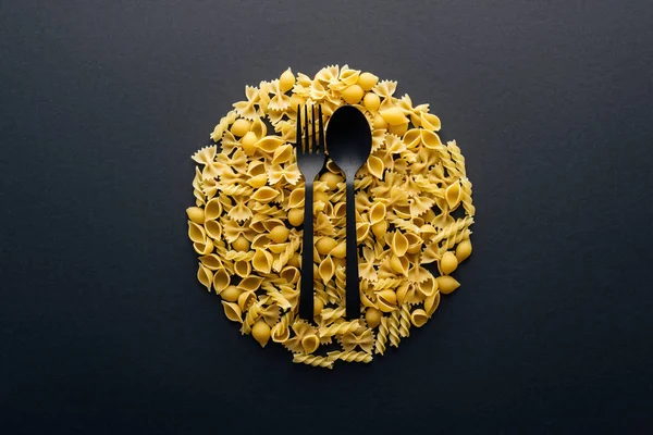 Top view of plate concept with plastic black fork and spoon isolated on black — Stock Photo