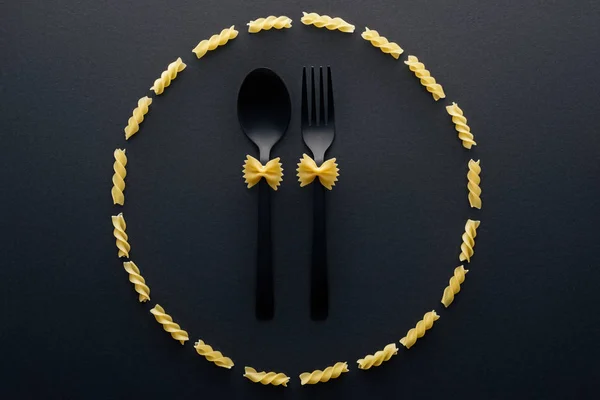 Top view of farfalle pasta on spoon and fork in circle from rotini pasta — Stock Photo