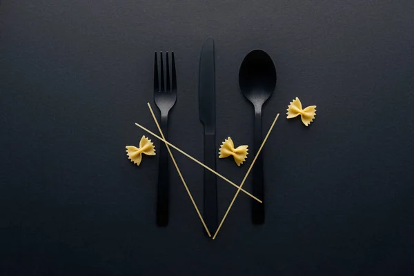 Couverts en plastique avec farfalle pâtes et spaghettis sur fond noir — Photo de stock