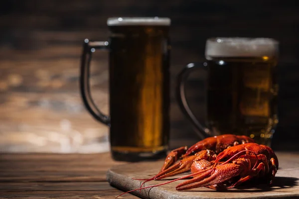 Enfoque selectivo de langostas rojas y vasos con cerveza en la superficie de madera - foto de stock