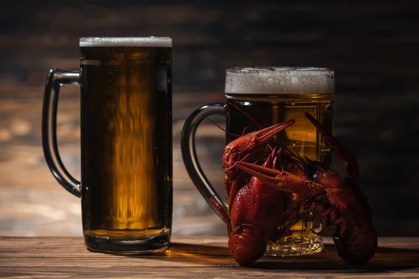 Copos com cerveja e lagostas vermelhas na superfície de madeira — Fotografia de Stock