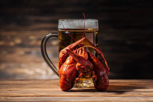 Glass with beer and red lobsters on wooden surface — Stock Photo