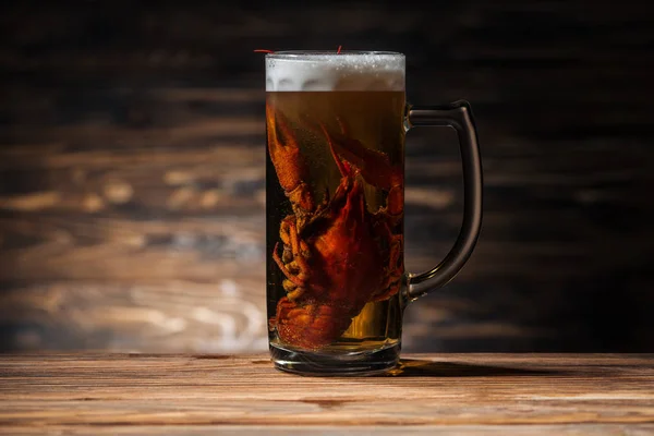 Red lobster in glass with beer on wooden surface — Stock Photo