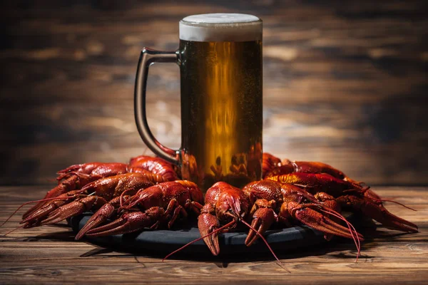 Vidro com cerveja na placa com lagostas vermelhas na superfície de madeira — Fotografia de Stock