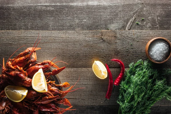 Vue de dessus des homards rouges, de l'aneth, des tranches de citron, du poivre et du sel sur la surface en bois — Photo de stock