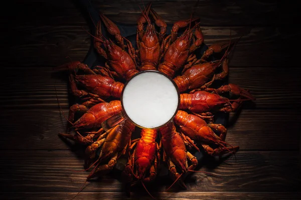 Top view of glass of beer on plate with red lobsters at wooden surface — Stock Photo